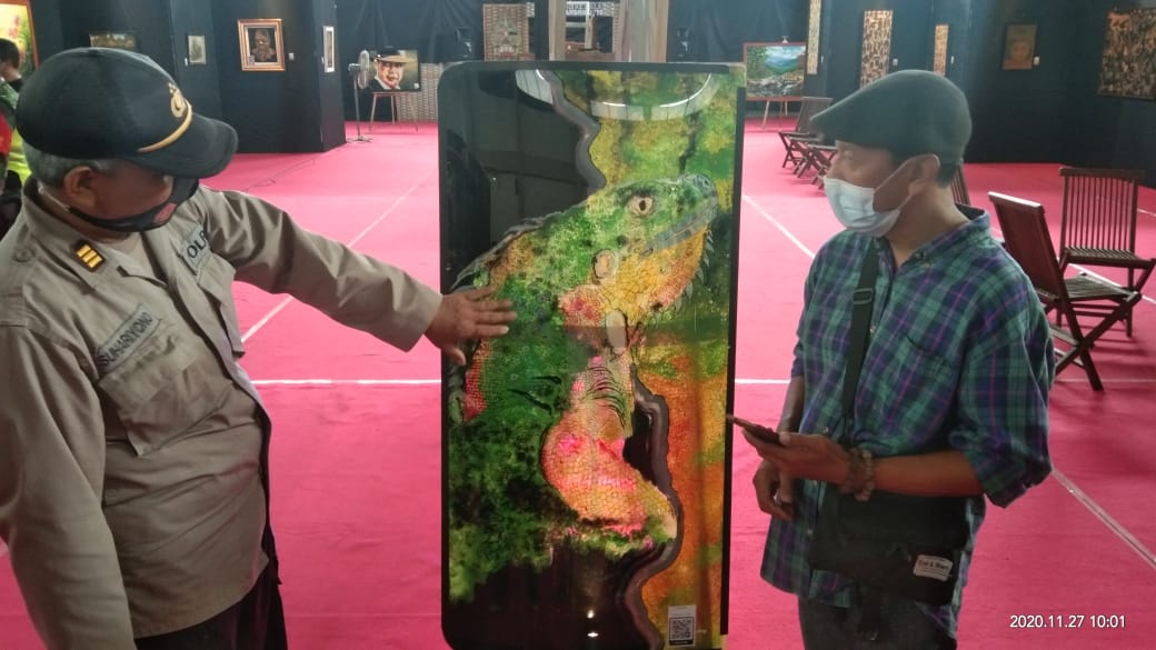 Perupa Budiyanto menunjukkan hasil karya lukisannya melalui media kaca. (Foto : noyo ) 