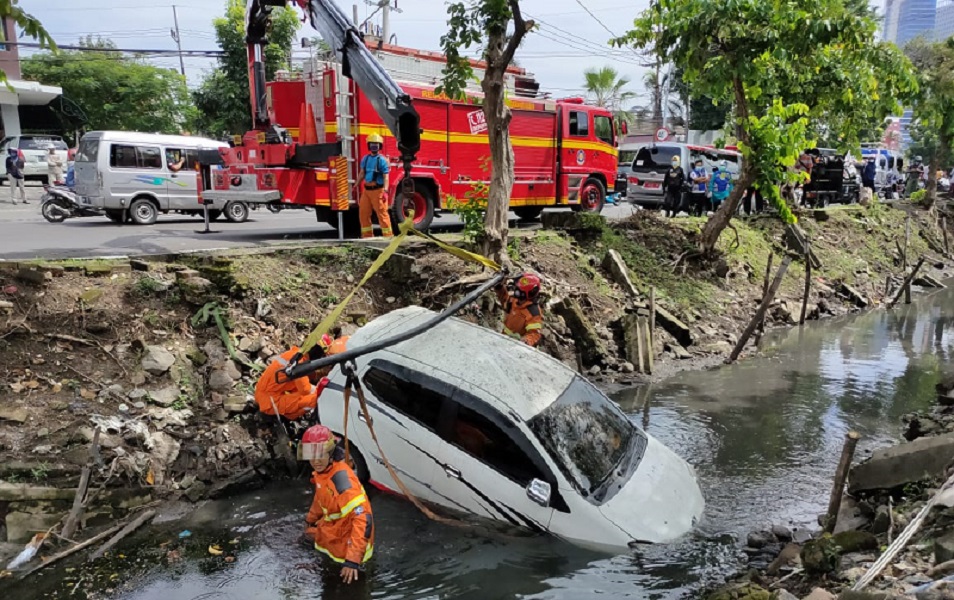 Mobil Toyota Agya tercebur ke sungai Jalan Jemursari, Surabaya, Selasa (23/2/2021), akibat pengemudi berkendara sambil main HP.