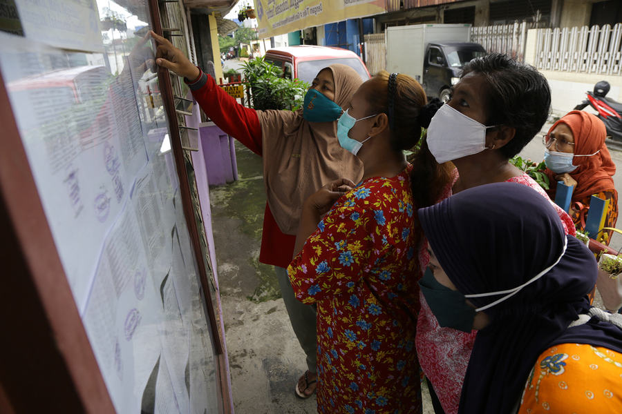 Penempelan data penerima bansos di lingkungan warga Surabaya.
