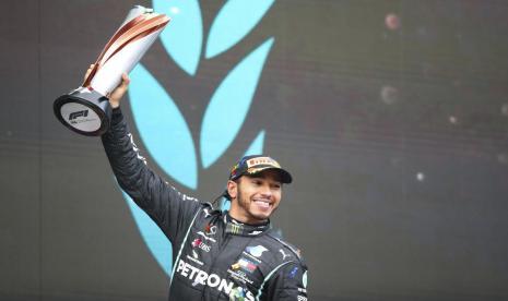 Pembalap Mercedes, Lewis Hamilton mengangkat trofi juara GP Turki setelah berhasil finis terdepan, Minggu (15/11). 