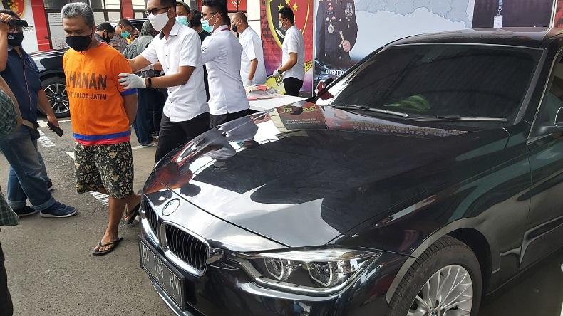 Tersangka kasus penipuan saat diamankan di Mapolda Jatim beserta barang bukti mobil BMW. 