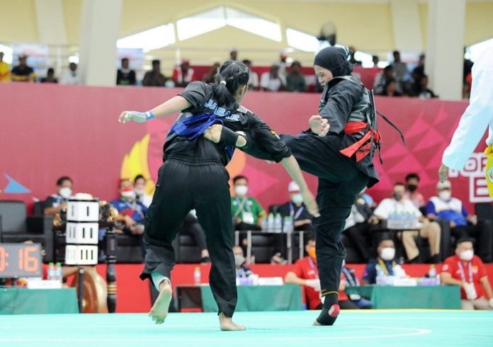 Sarah Tria Monita (sabuk merah) menendang pesilat Jabar Shalima Lushiana (sabuk biru) dengan kaki kiri saat final kelas E putri di GOR Toware, Kabupaten Jayapura, Papua, Selasa (12/10/2021).